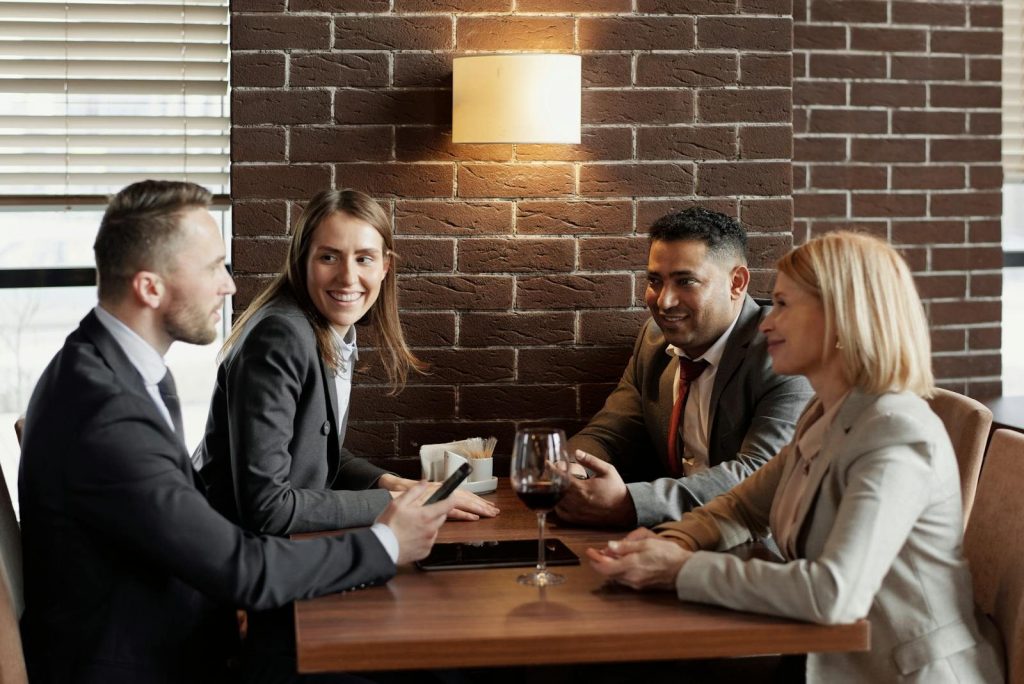 A group of business professionals having a lively discussion in a modern café setting.
